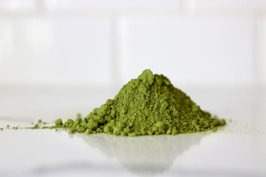 mound of vibrant green matcha tea on countertop with reflection